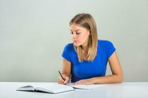 Portrait of beautiful female student sitting at the table and studying. photo