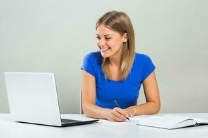 Beautiful female student using laptop and studying. photo