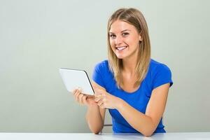 Portrait of beautiful young woman sitting at the table and using digital tablet photo