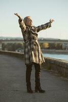 Senior woman enjoys standing by the river with her arms outstretched.Toned image. photo