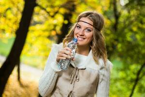 hermosa boho niña disfruta Bebiendo agua en el parque. foto