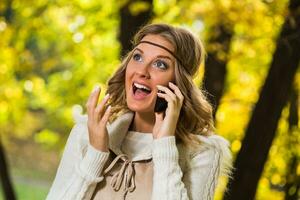 Beautiful boho girl enjoys talking on the phone in the park. photo