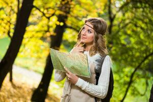 Beautiful boho girl enjoys spending time in the forest with travel map. photo