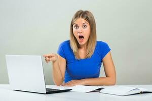 Excited female student pointing at  laptop while  studying. photo