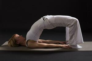 Woman exercising yoga indoor on black background, photo