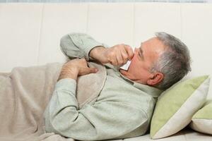 Senior man is sneezing into handkerchief. photo