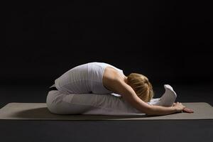 Woman exercising yoga indoor on black background, photo