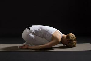Woman exercising yoga indoor on black background, photo