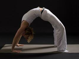 Woman exercising yoga indoor on black background, photo