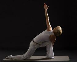 Woman exercising yoga indoor on black background, photo