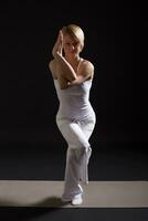 Woman exercising yoga indoor on black background, photo