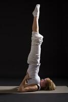 Woman exercising yoga indoor on black background, photo