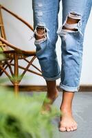 Bare feet woman wearing ripped jeans on terrace. photo