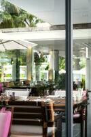 Hotel restaurant space with tables set for dinner at luxury resort, view through by window. photo