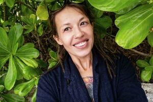 Funny smiling woman taking selfies among tropical leaves. photo