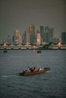 long tail boat in chaopraya river and bangkok skyscraper background photo