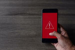 Smartphone with triangle caution warning icon. Copy space for text. System error, malware and cyber crime concept. photo