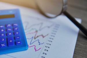 Closeup image of calculator, magnifying glass and line graph. Data and finance analysis, business intelligence and trends concept. photo