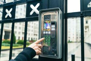 Female Hand Operating Video Intercom System, Dialing Apartment Number in Urban Residential Complex photo