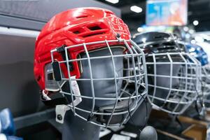 Blue and Red Hockey Helmets with Visors Arranged Neatly on the Shelf photo