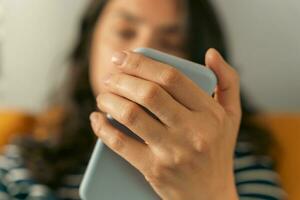 Dark-Haired Middle-Aged Woman Enjoying News on Smartphone at Home photo