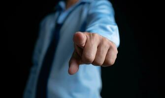 Employee makes a forward pointing gesture on a dark background. photo