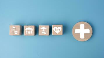 Concept of health insurance and medical. Wooden block with icons about health insurance and access to health care, health care planning on a blue background. photo