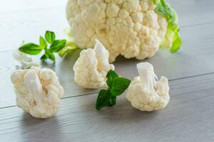 slices of raw small raw cauliflower on wooden table photo