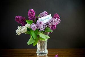 bouquet of different blooming spring lilacs in a vase on black background photo