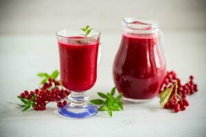 recién exprimido grueso natural jugo con pulpa desde maduro rojo viburnum en un licorera foto