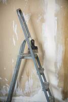 old stepladder on the background of plastered walls photo