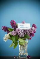 bouquet of different blooming spring lilacs in a vase on blue background photo