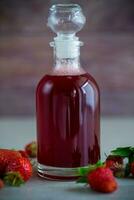 sweet cooked strawberry syrup in a glass decanter photo