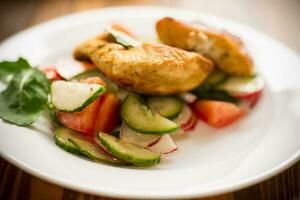 fried chicken fillet with fresh cucumbers, tomatoes and radishes in a plate photo