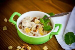 cooked boiled sweet oatmeal with nuts and candied fruits in a bowl photo