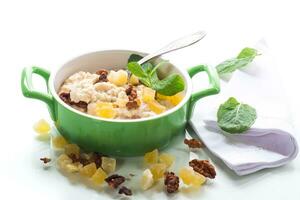 cooked boiled sweet oatmeal with nuts and candied fruits in a bowl photo