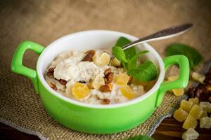 cooked boiled sweet oatmeal with nuts and candied fruits in a bowl photo