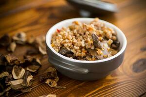 boiled buckwheat with organic forest dried mushrooms in a ceramic bowl photo