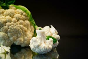 slices of raw small raw cauliflower on black background photo