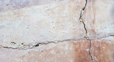 concrete wall has cracks in 4 directions, the exterior is plastered with red gray cement photo