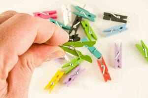 a person holding a small piece of colored clothes pegs photo