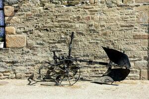 a black plow is leaning against a stone wall photo