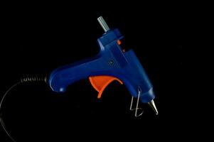 un azul y naranja pegamento pistola en un negro antecedentes foto