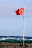 a red flag on the beach near the ocean photo