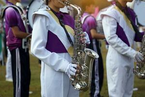 Orchestra students play saxophones in a parade at the school's athletics event. Soft and selective focus. photo