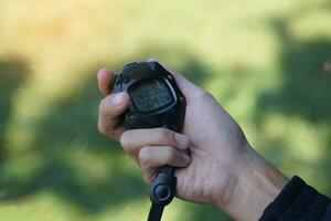 Coach holds a stopwatch to check the runners' speed statistics during practice. soft and selective focus. photo