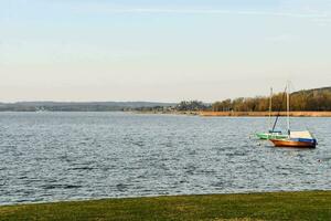 two boats are docked on the shore of a lake photo