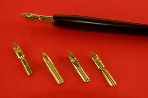 a fountain pen with four gold nibs and a black pen photo