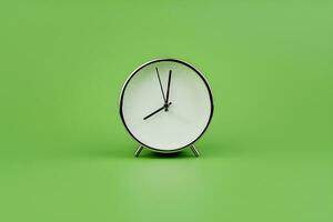 White modern alarm clock on a light green background. Time concept and working with precious time photo