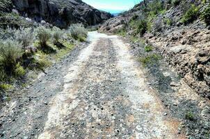 a dirt road in the mountains with rocks and bushes photo